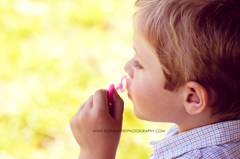 Little boy in the park blowing bubbles 