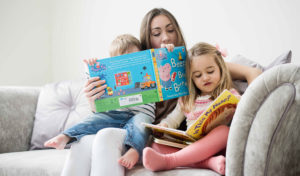 Mum and young kids reading a book.