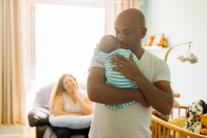 Daddy carrying newborn on shoulders.