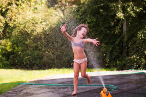 Girl playing in sprinkler by Essex child photographer Kofo Baptist.