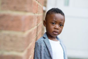 Young boy leaning against a wall by London child photographer Kofo Baptist.