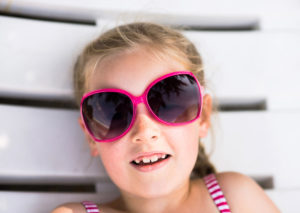 Little girl in pool wearing sunglasses and swimsuit
