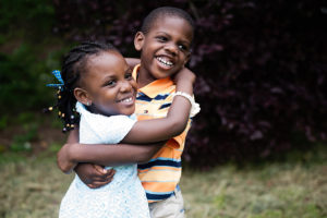 Portrait of happy siblings hugging each other, smiling at camera.