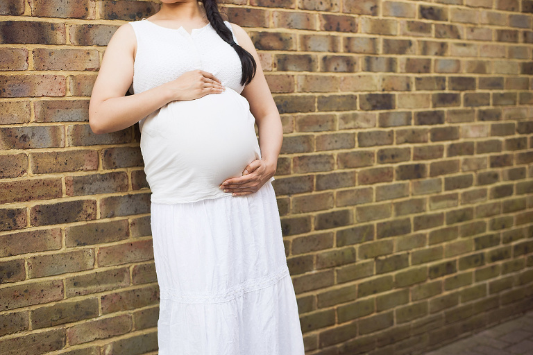 Pregnant woman with hands on bump.