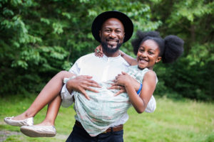 Dad carries his young daughter in the park.