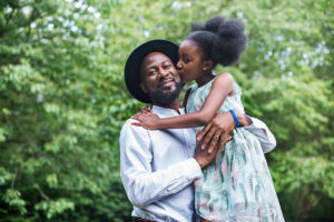 Daughter kisses her dad on the cheeks.