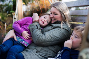 Mother and children sit on homemade swing.