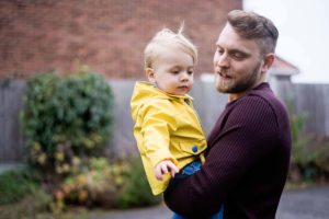 Dad carries toddler outdoors.