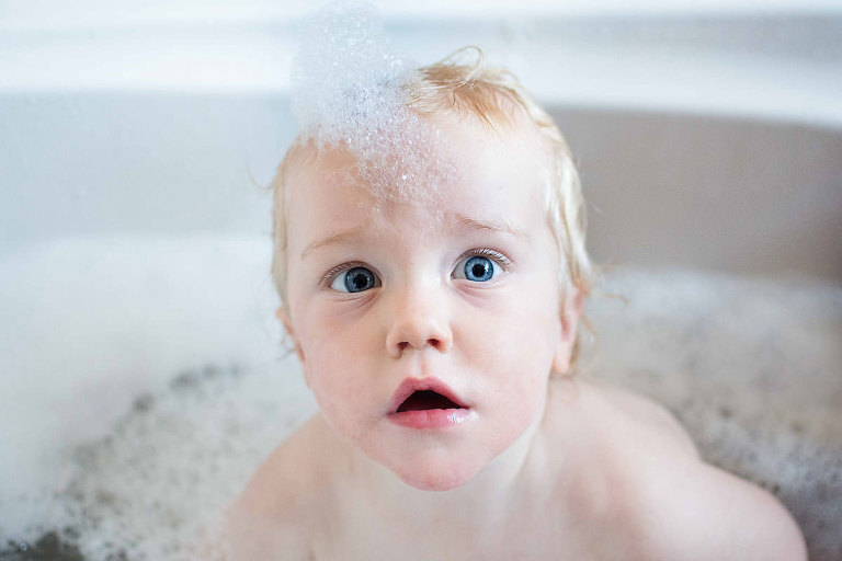 London child photographer photographs toddler having a bubble bath.