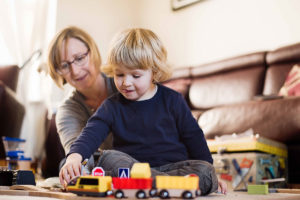 Little boy plays with toy train set.