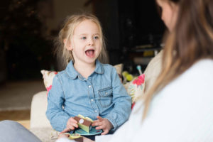 Little girl and mum talk on sofa.