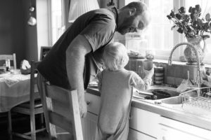 Dad and son get water from kitchen sink
