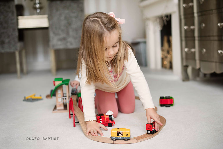 Little girl playing with toy train tracks