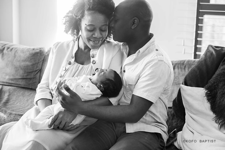Dad leans to kiss while mum holds baby