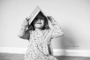 Young girl puts book over her head.